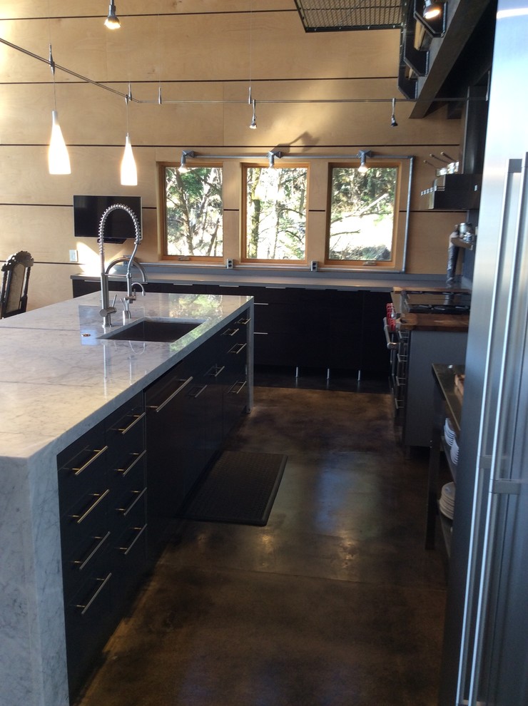 Photo of a medium sized urban l-shaped open plan kitchen in Other with a submerged sink, flat-panel cabinets, black cabinets, quartz worktops, black splashback, stone tiled splashback, stainless steel appliances, concrete flooring and an island.