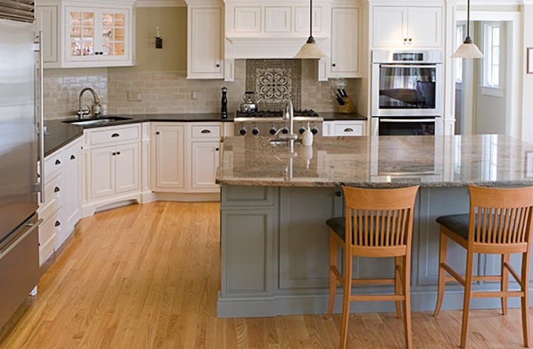 Exempel på ett mellanstort klassiskt kök, med en undermonterad diskho, luckor med infälld panel, vita skåp, granitbänkskiva, beige stänkskydd, stänkskydd i tunnelbanekakel, rostfria vitvaror, ljust trägolv, en köksö och brunt golv