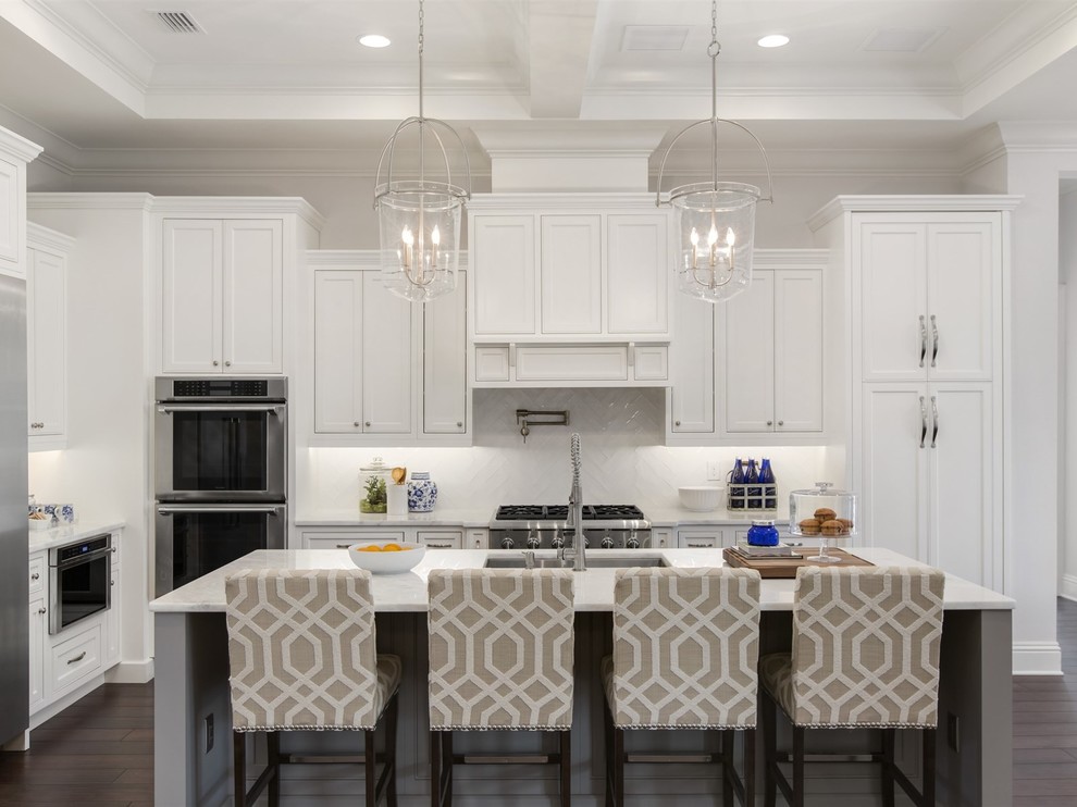 Large traditional l-shaped kitchen/diner in Orlando with a submerged sink, shaker cabinets, white cabinets, marble worktops, white splashback, ceramic splashback, stainless steel appliances, dark hardwood flooring and an island.