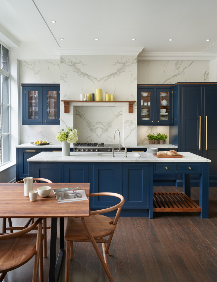 Eat-in kitchen - mid-sized traditional galley vinyl floor and brown floor eat-in kitchen idea in London with an undermount sink, shaker cabinets, blue cabinets, solid surface countertops, white backsplash, porcelain backsplash, stainless steel appliances and an island