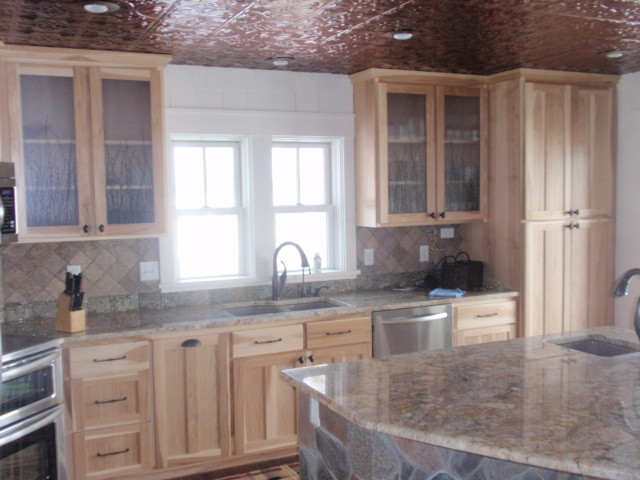 Bild på ett mellanstort rustikt kök, med en dubbel diskho, luckor med glaspanel, skåp i ljust trä, granitbänkskiva, beige stänkskydd, stänkskydd i keramik, rostfria vitvaror, mörkt trägolv, en köksö och brunt golv