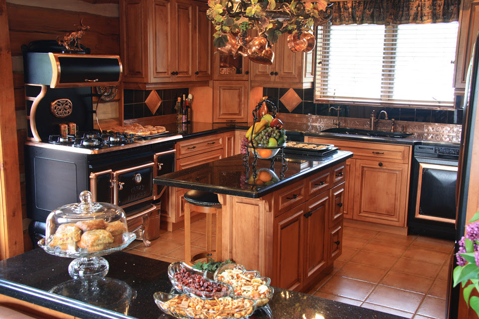 Example of a mid-sized classic u-shaped terra-cotta tile and brown floor enclosed kitchen design in New York with an undermount sink, raised-panel cabinets, medium tone wood cabinets, terrazzo countertops, black backsplash, ceramic backsplash, black appliances and an island