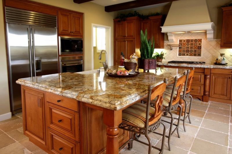 Inspiration for a large country l-shaped cement tile floor and beige floor enclosed kitchen remodel in Kansas City with raised-panel cabinets, medium tone wood cabinets, granite countertops, beige backsplash, mosaic tile backsplash, paneled appliances, an island and a farmhouse sink