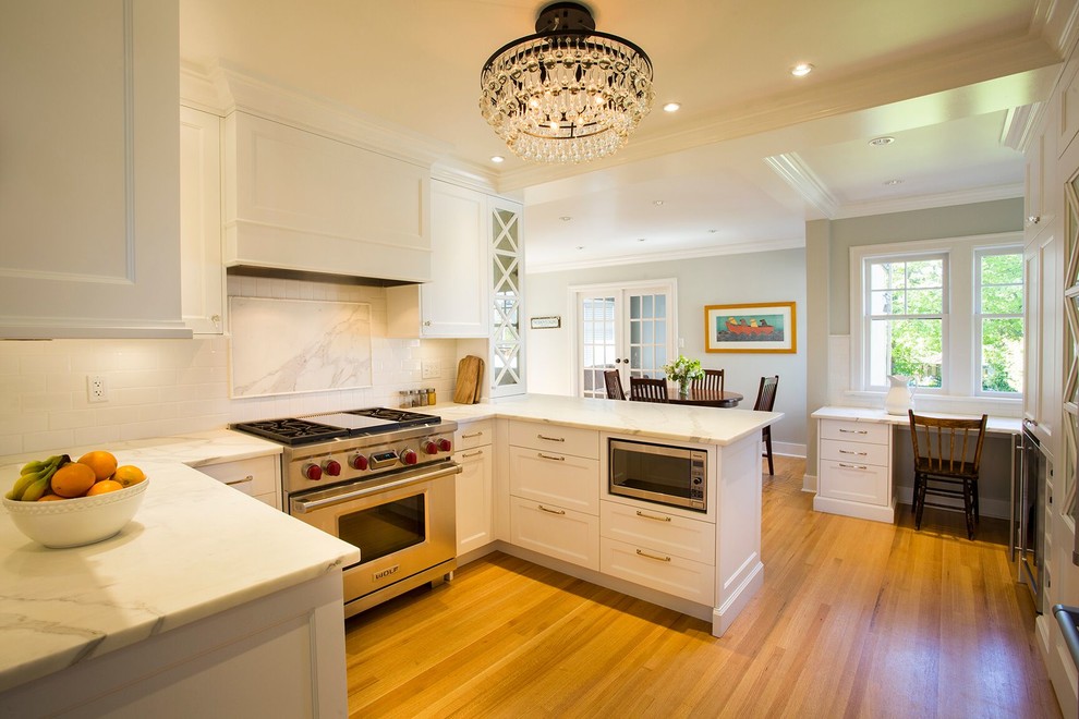 Exempel på ett mellanstort klassiskt kök, med luckor med infälld panel, vita skåp, bänkskiva i kvartsit, vitt stänkskydd, stänkskydd i tunnelbanekakel, rostfria vitvaror, ljust trägolv, brunt golv och en undermonterad diskho