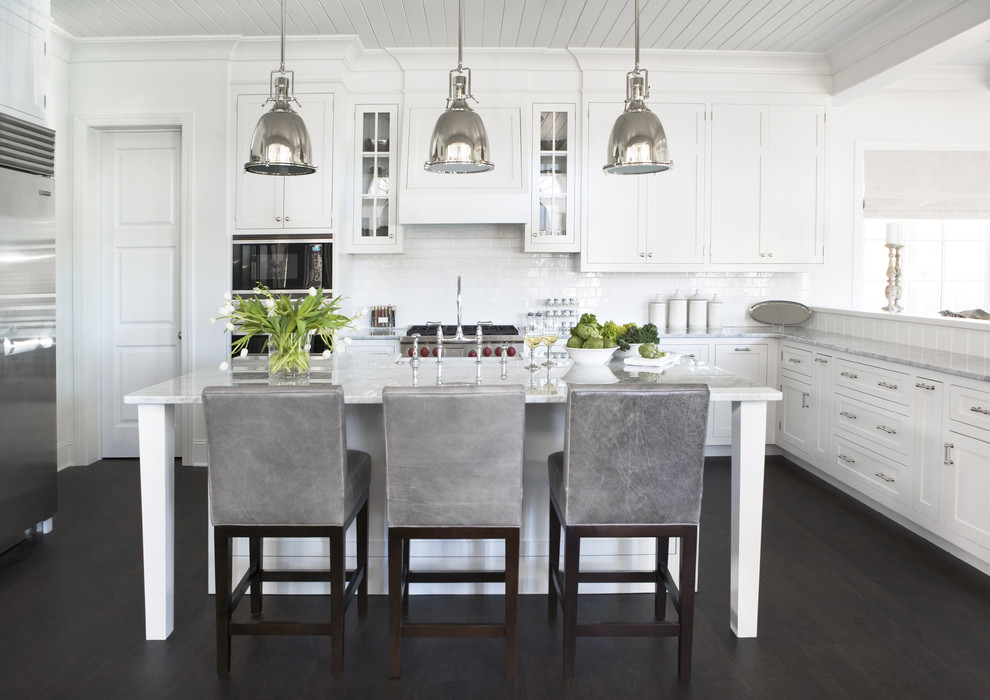 Inspiration for a large contemporary u-shaped dark wood floor kitchen remodel in Other with stainless steel appliances, shaker cabinets, white cabinets, marble countertops, white backsplash, subway tile backsplash and an island