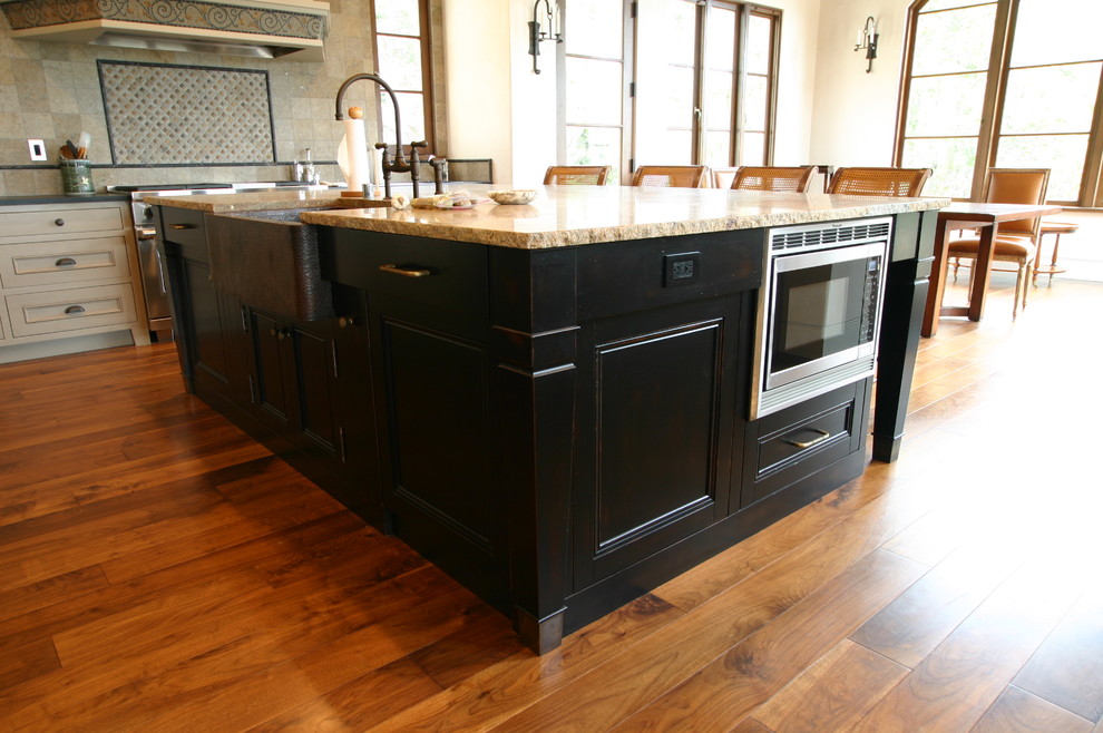 Bild på ett stort amerikanskt kök, med en rustik diskho, luckor med profilerade fronter, beige skåp, granitbänkskiva, flerfärgad stänkskydd, stänkskydd i stenkakel, rostfria vitvaror, mellanmörkt trägolv och en köksö