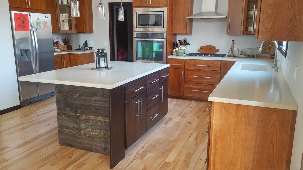 Inspiration for a mid-sized transitional l-shaped light wood floor eat-in kitchen remodel in Other with an undermount sink, flat-panel cabinets, medium tone wood cabinets, concrete countertops, white backsplash, stainless steel appliances and an island