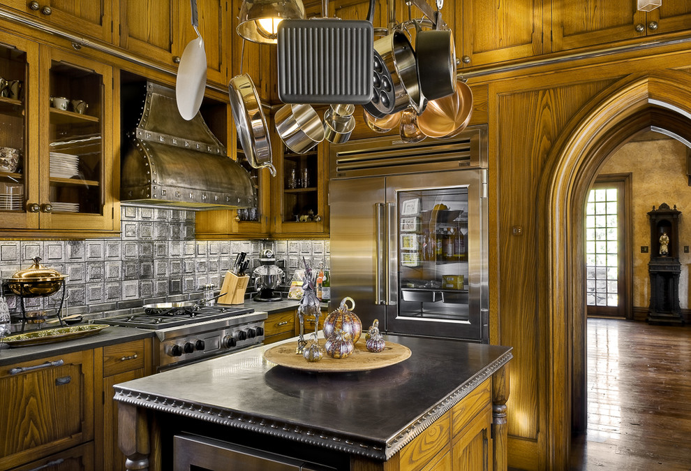 This is an example of a victorian kitchen in Portland Maine with recessed-panel cabinets, medium wood cabinets, grey splashback, stainless steel appliances, dark hardwood flooring and an island.