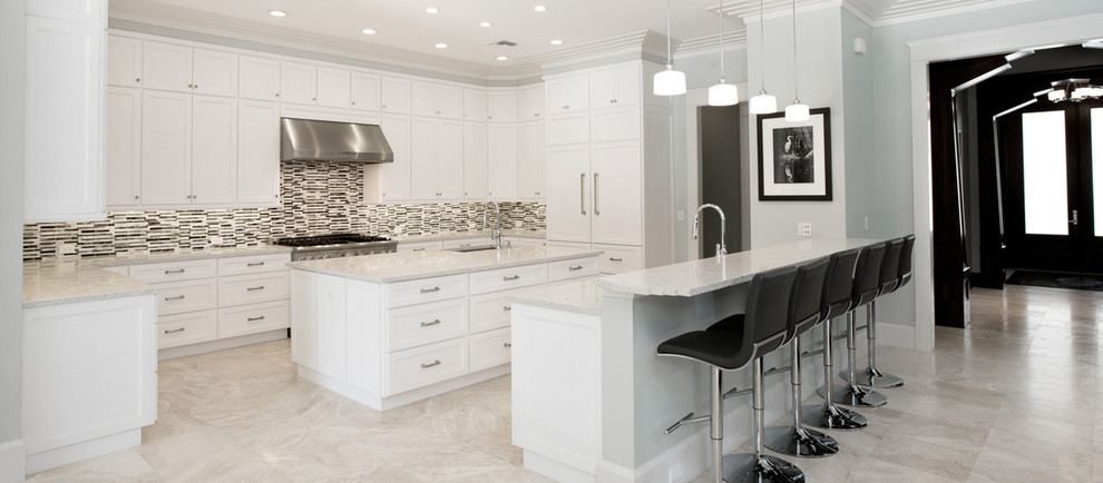 Example of a large trendy u-shaped marble floor and beige floor open concept kitchen design in Miami with an undermount sink, shaker cabinets, white cabinets, quartzite countertops, multicolored backsplash, matchstick tile backsplash, paneled appliances and two islands