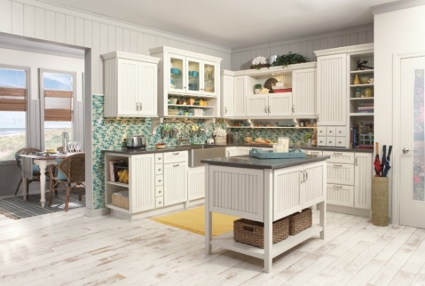 Bild på ett maritimt kök och matrum, med en rustik diskho, luckor med lamellpanel, vita skåp, blått stänkskydd, stänkskydd i glaskakel, målat trägolv och en köksö