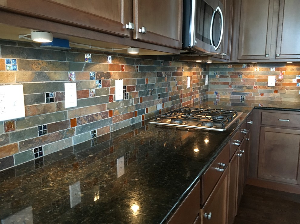Inspiration for a rustic dark wood floor and brown floor kitchen remodel in Denver with recessed-panel cabinets, dark wood cabinets, granite countertops, multicolored backsplash, slate backsplash and stainless steel appliances
