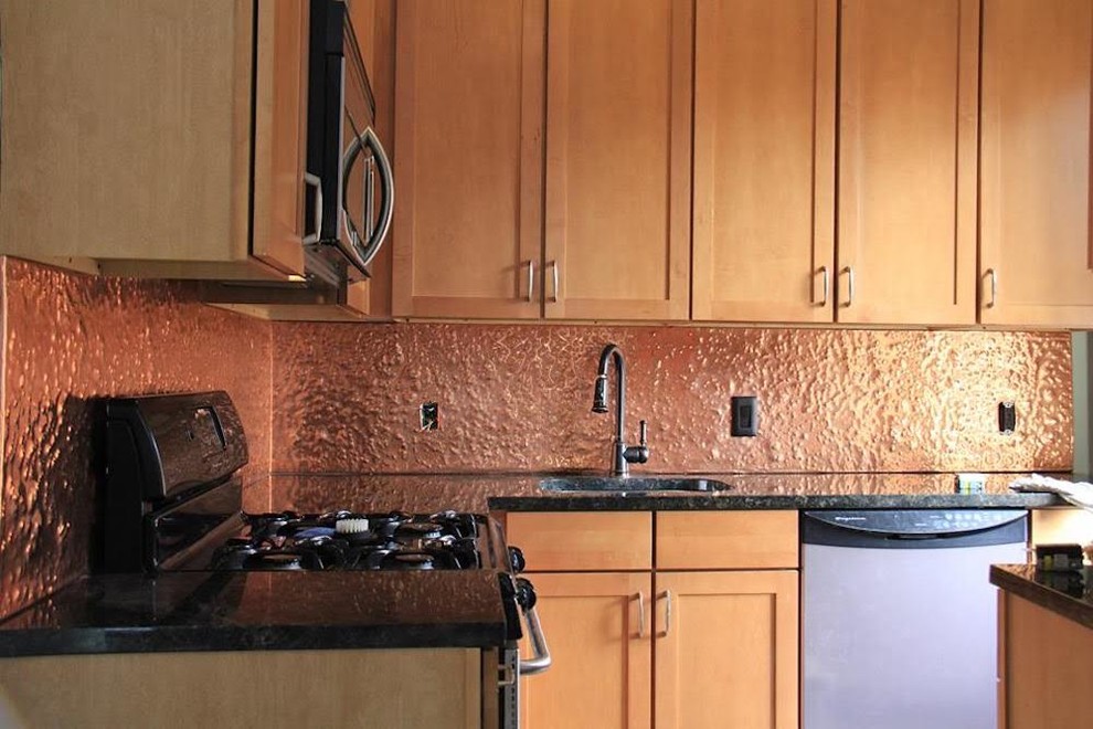Bild på ett mellanstort funkis svart svart kök, med en undermonterad diskho, skåp i shakerstil, skåp i ljust trä, granitbänkskiva, orange stänkskydd, stänkskydd i metallkakel, rostfria vitvaror och en köksö