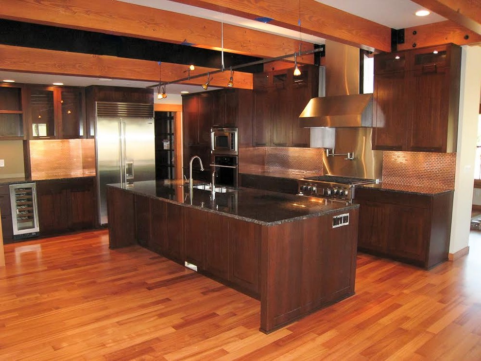 Photo of a medium sized classic l-shaped kitchen/diner in Seattle with a submerged sink, shaker cabinets, dark wood cabinets, granite worktops, red splashback, mosaic tiled splashback, stainless steel appliances, medium hardwood flooring and an island.