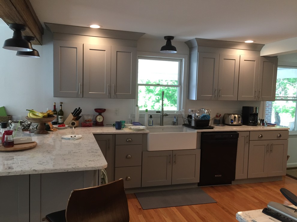 Mid-sized elegant l-shaped medium tone wood floor and brown floor open concept kitchen photo in DC Metro with a farmhouse sink, raised-panel cabinets, gray cabinets, granite countertops, black appliances and a peninsula
