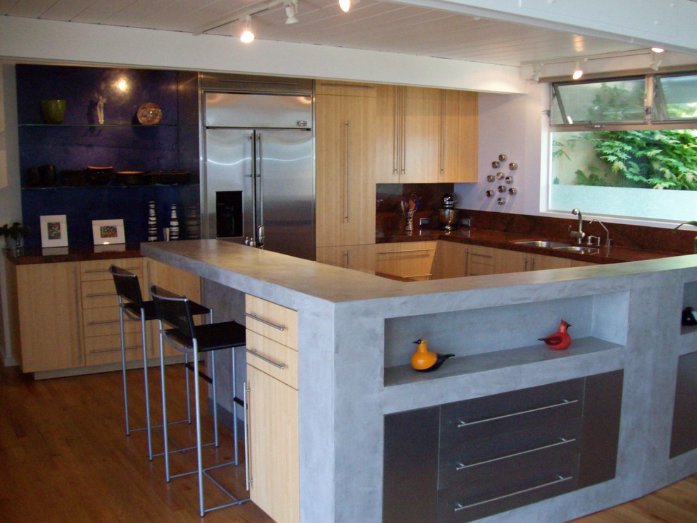 Пример оригинального дизайна: большая угловая кухня в стиле модернизм с обеденным столом, плоскими фасадами, светлыми деревянными фасадами, столешницей из бетона, техникой из нержавеющей стали и островом