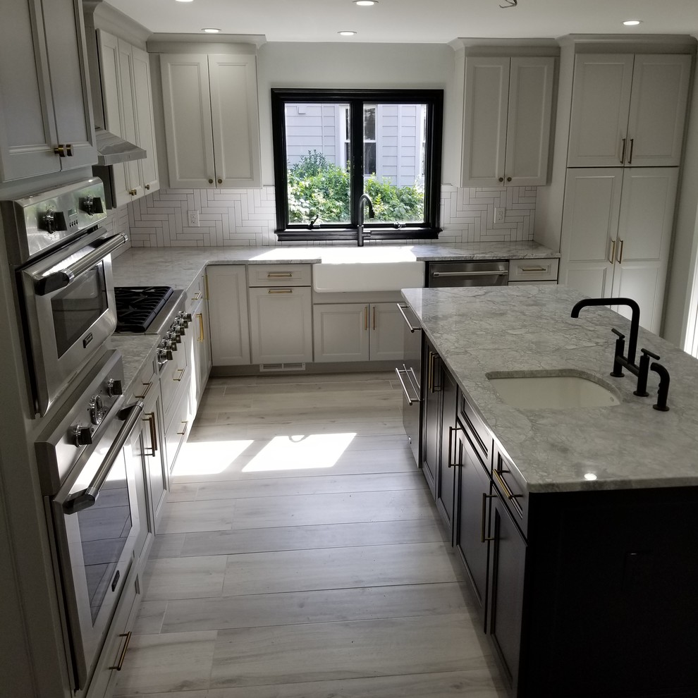This is an example of a medium sized traditional l-shaped open plan kitchen in New York with a submerged sink, recessed-panel cabinets, white cabinets, granite worktops, white splashback, ceramic splashback, stainless steel appliances, laminate floors, an island, grey floors and multicoloured worktops.