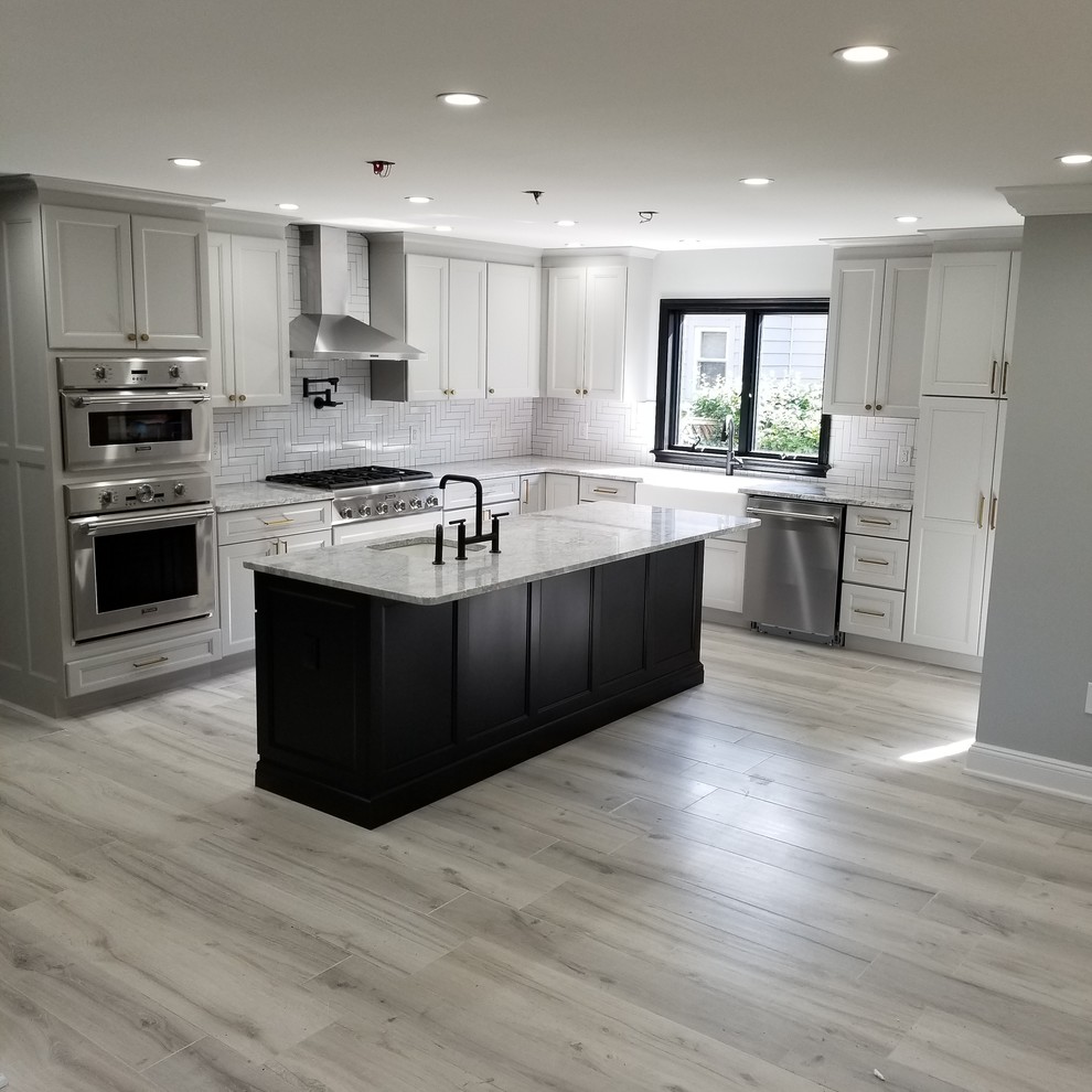 Inredning av ett klassiskt mellanstort flerfärgad flerfärgat kök, med en undermonterad diskho, luckor med infälld panel, vita skåp, granitbänkskiva, vitt stänkskydd, stänkskydd i keramik, rostfria vitvaror, laminatgolv, en köksö och grått golv
