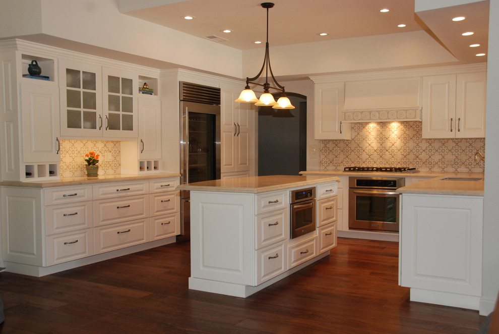 Example of a large transitional u-shaped dark wood floor and brown floor enclosed kitchen design in Chicago with an undermount sink, raised-panel cabinets, white cabinets, limestone countertops, multicolored backsplash, mosaic tile backsplash, stainless steel appliances and an island