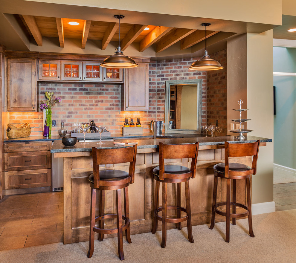 Bild på ett mellanstort rustikt kök, med en undermonterad diskho, skåp i shakerstil, skåp i mellenmörkt trä, bänkskiva i täljsten, rött stänkskydd, stänkskydd i tegel, rostfria vitvaror, skiffergolv, en halv köksö och brunt golv