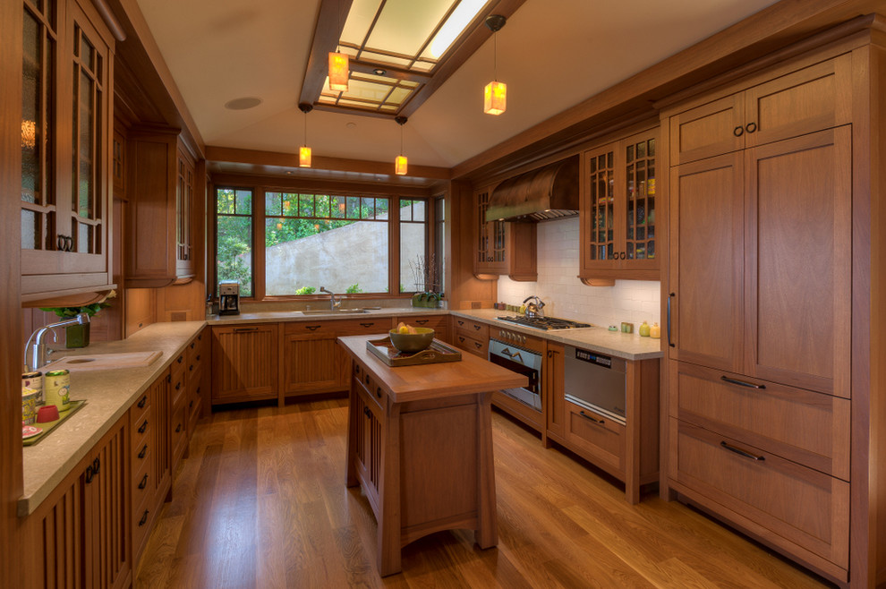 Design ideas for a traditional u-shaped kitchen in San Francisco with a built-in sink, glass-front cabinets, medium wood cabinets, wood worktops, white splashback, integrated appliances, medium hardwood flooring, an island and orange floors.