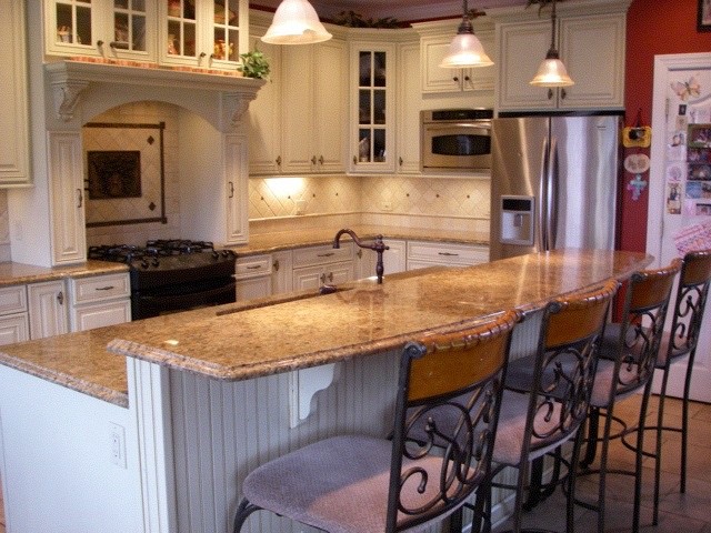 Inredning av ett medelhavsstil avskilt, mellanstort l-kök, med en undermonterad diskho, luckor med upphöjd panel, vita skåp, granitbänkskiva, beige stänkskydd, stänkskydd i keramik, rostfria vitvaror, klinkergolv i keramik och en köksö