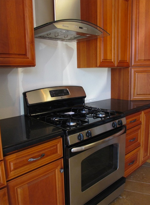 Immagine di una cucina parallela chic chiusa e di medie dimensioni con ante in legno scuro e elettrodomestici in acciaio inossidabile