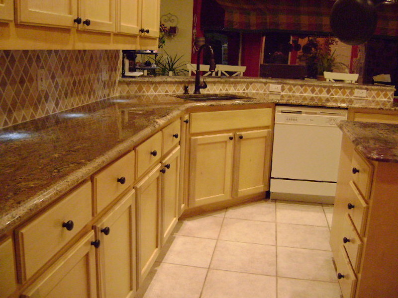 Klassisk inredning av ett mellanstort kök, med en nedsänkt diskho, luckor med upphöjd panel, skåp i ljust trä, granitbänkskiva, flerfärgad stänkskydd, stänkskydd i terrakottakakel, vita vitvaror, klinkergolv i porslin och en köksö