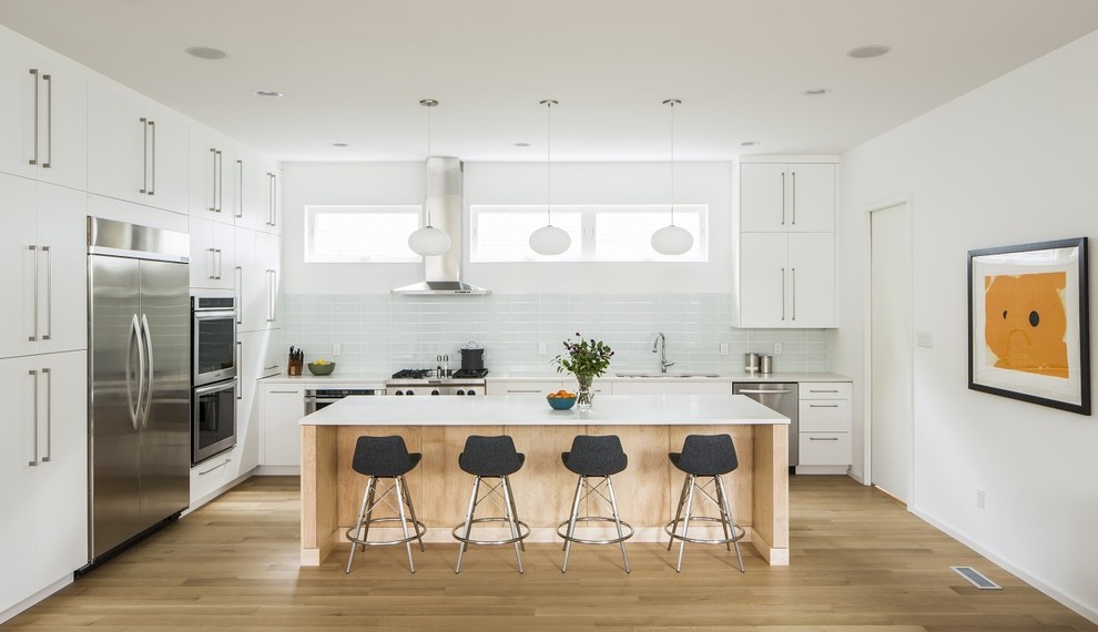 Ejemplo de cocina escandinava de tamaño medio con fregadero bajoencimera, armarios con paneles lisos, puertas de armario blancas, encimera de cuarzo compacto, salpicadero blanco, salpicadero de azulejos de vidrio, electrodomésticos de acero inoxidable, suelo de madera clara y una isla