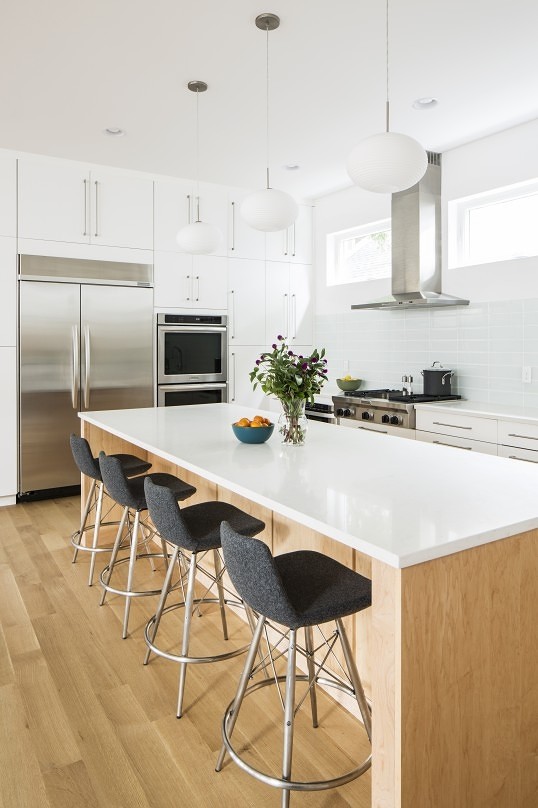Eat-in kitchen - mid-sized scandinavian l-shaped light wood floor eat-in kitchen idea in Little Rock with flat-panel cabinets, an island, an undermount sink, white cabinets, quartz countertops, white backsplash, glass tile backsplash and stainless steel appliances