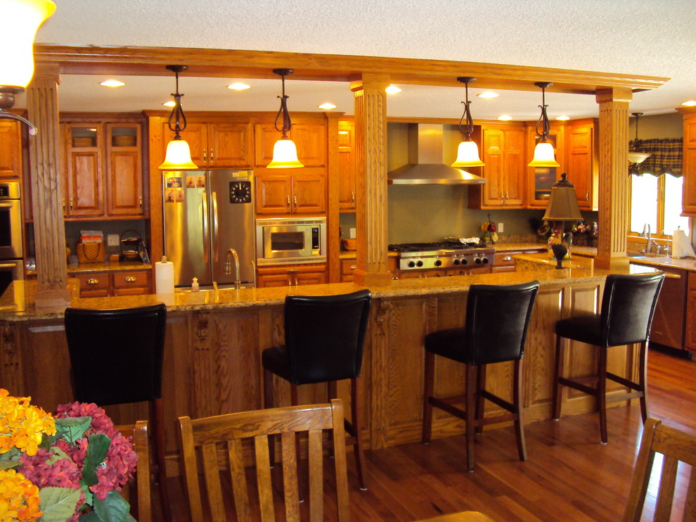 Exempel på ett stort klassiskt kök, med luckor med upphöjd panel, skåp i mellenmörkt trä, rostfria vitvaror, mellanmörkt trägolv, en köksö, brunt golv, en dubbel diskho och granitbänkskiva