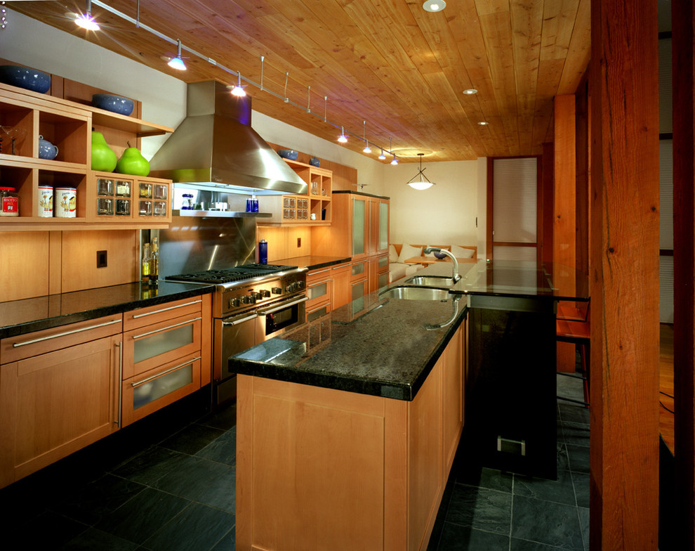 Idéer för ett avskilt, mellanstort modernt svart linjärt kök, med en undermonterad diskho, skåp i shakerstil, skåp i ljust trä, brunt stänkskydd, stänkskydd i trä, rostfria vitvaror, skiffergolv, en köksö och svart golv