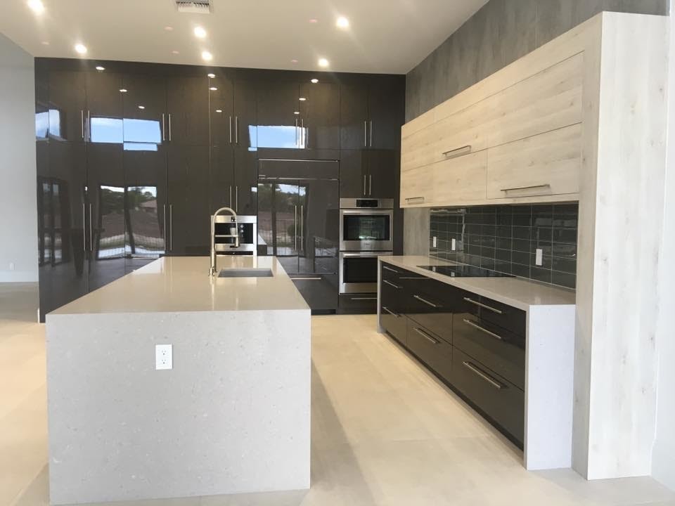 This is an example of a medium sized contemporary single-wall kitchen/diner in Miami with a submerged sink, flat-panel cabinets, black cabinets, grey splashback, glass tiled splashback, integrated appliances and an island.