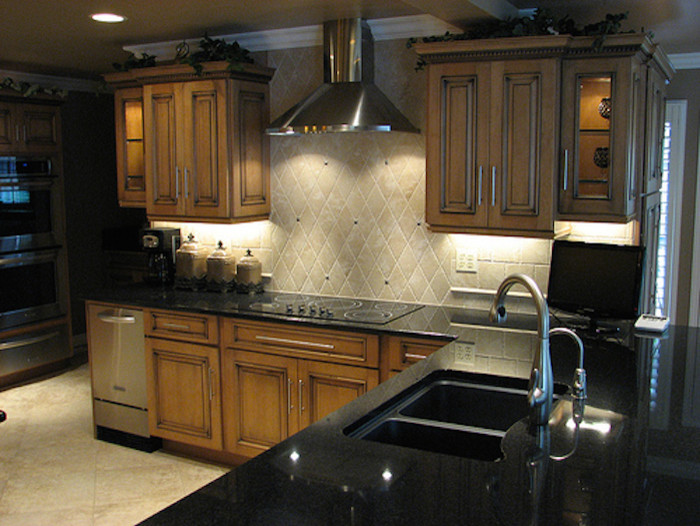 Example of a mid-sized classic l-shaped ceramic tile eat-in kitchen design in Wichita with a double-bowl sink, recessed-panel cabinets, brown cabinets, granite countertops, beige backsplash, stone tile backsplash, stainless steel appliances and no island