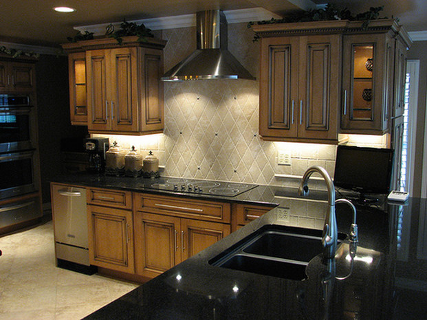 This is an example of a medium sized classic u-shaped kitchen in Wichita with a double-bowl sink, raised-panel cabinets, beige splashback, porcelain splashback, stainless steel appliances, porcelain flooring and beige floors.