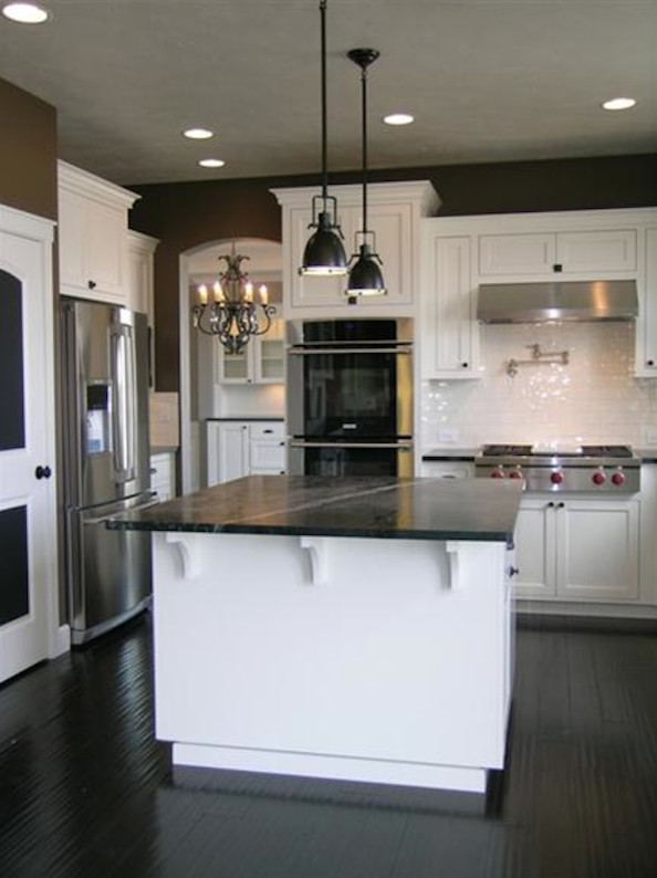 Foto på ett funkis kök, med en dubbel diskho, luckor med infälld panel, vita skåp, bänkskiva i täljsten, vitt stänkskydd, stänkskydd i keramik, rostfria vitvaror, linoleumgolv och en köksö