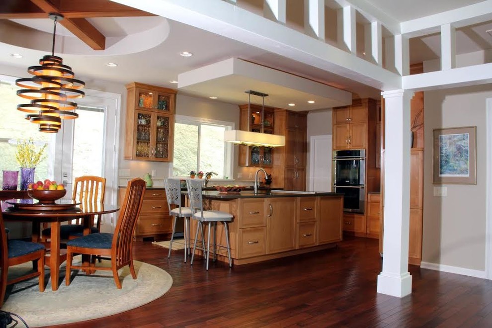 Klassisk inredning av ett mellanstort kök, med luckor med infälld panel, skåp i mellenmörkt trä, rostfria vitvaror, mellanmörkt trägolv, en köksö, en undermonterad diskho, granitbänkskiva och brunt golv