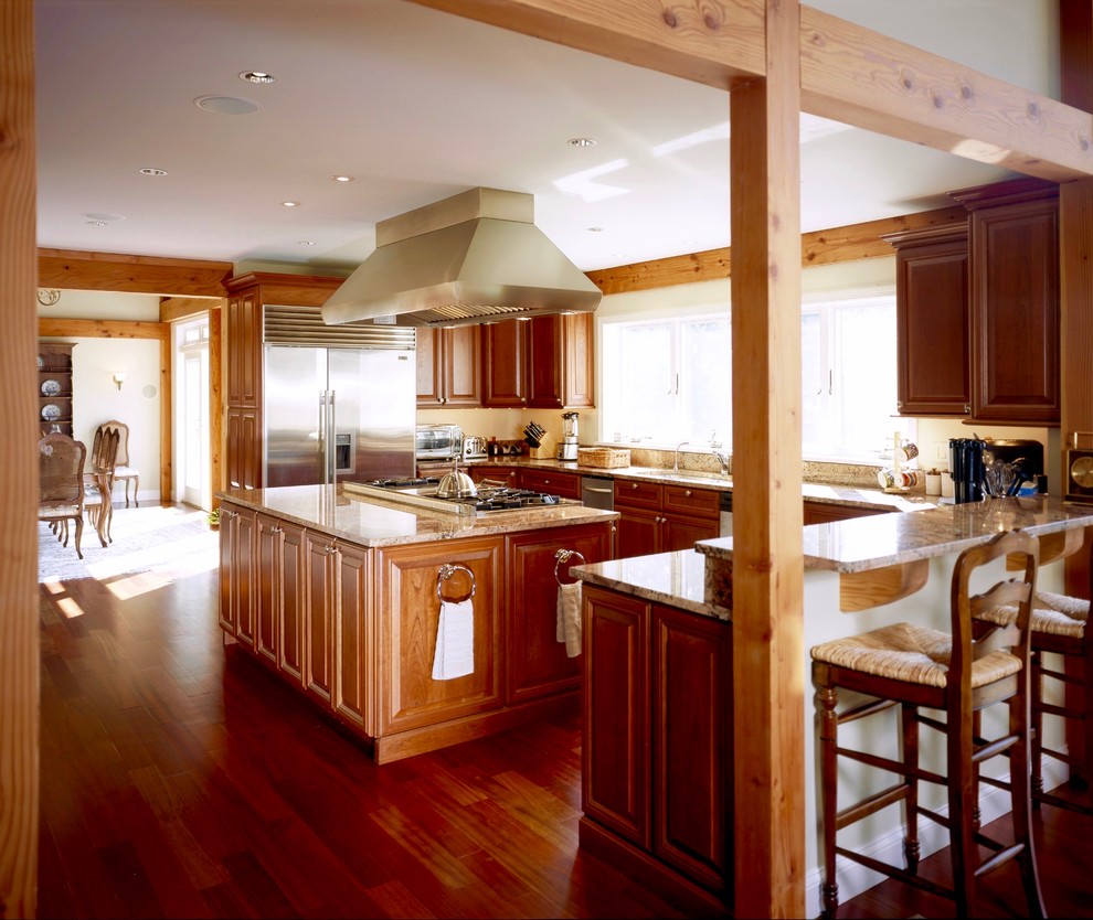 Foto på ett stort lantligt kök, med en undermonterad diskho, luckor med upphöjd panel, skåp i mörkt trä, granitbänkskiva, rostfria vitvaror, mörkt trägolv och en köksö