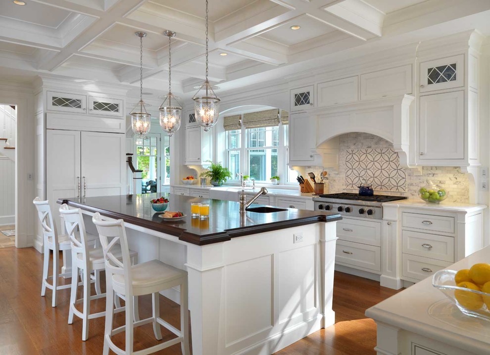 Klassische Küche in L-Form mit Kassettenfronten, weißen Schränken, bunter Rückwand, Küchengeräten aus Edelstahl, braunem Holzboden und Kücheninsel in Boston