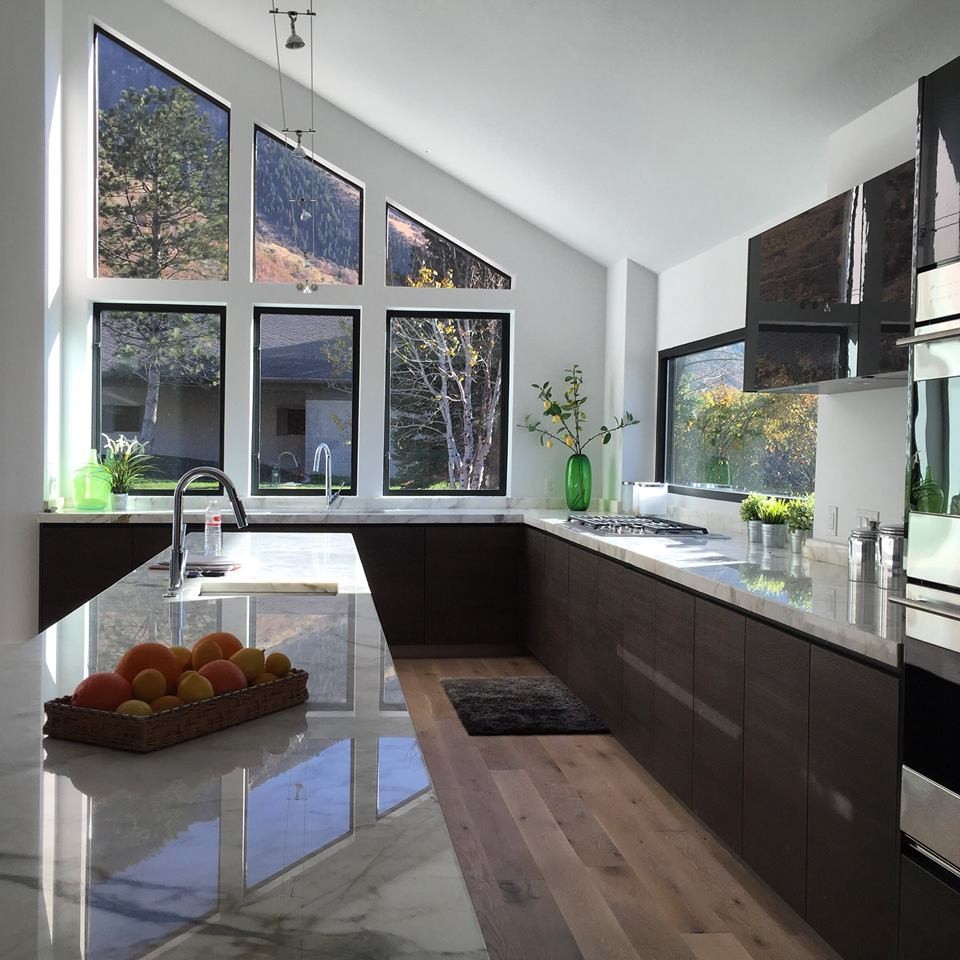 Bild på ett funkis kök och matrum, med släta luckor, skåp i mörkt trä, marmorbänkskiva, rostfria vitvaror, ljust trägolv och en undermonterad diskho