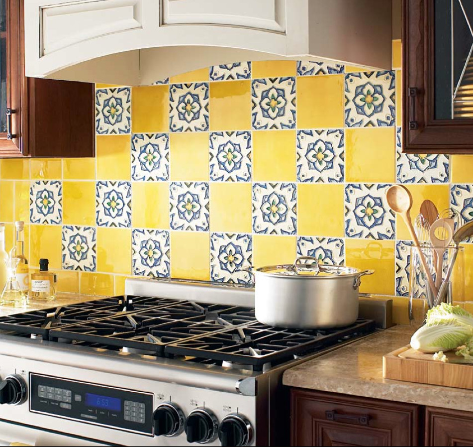 ニューヨークにある地中海スタイルのおしゃれなアイランドキッチン (セラミックタイルのキッチンパネル、シルバーの調理設備、ガラス扉のキャビネット、中間色木目調キャビネット、黄色いキッチンパネル) の写真