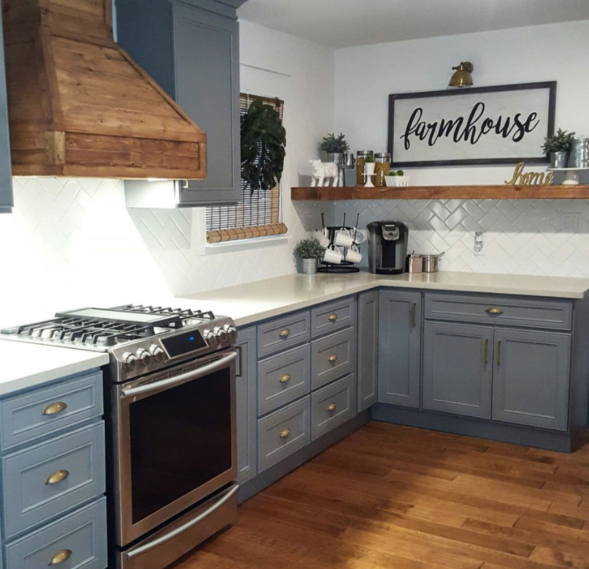 Example of a mid-sized farmhouse l-shaped medium tone wood floor and brown floor enclosed kitchen design in Other with recessed-panel cabinets, gray cabinets, quartz countertops, white backsplash, subway tile backsplash, stainless steel appliances, a peninsula and gray countertops