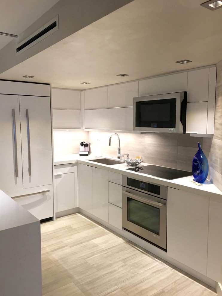 Photo of a medium sized contemporary u-shaped enclosed kitchen in Miami with a submerged sink, flat-panel cabinets, white cabinets, composite countertops, grey splashback, porcelain splashback, stainless steel appliances, light hardwood flooring, an island and grey floors.