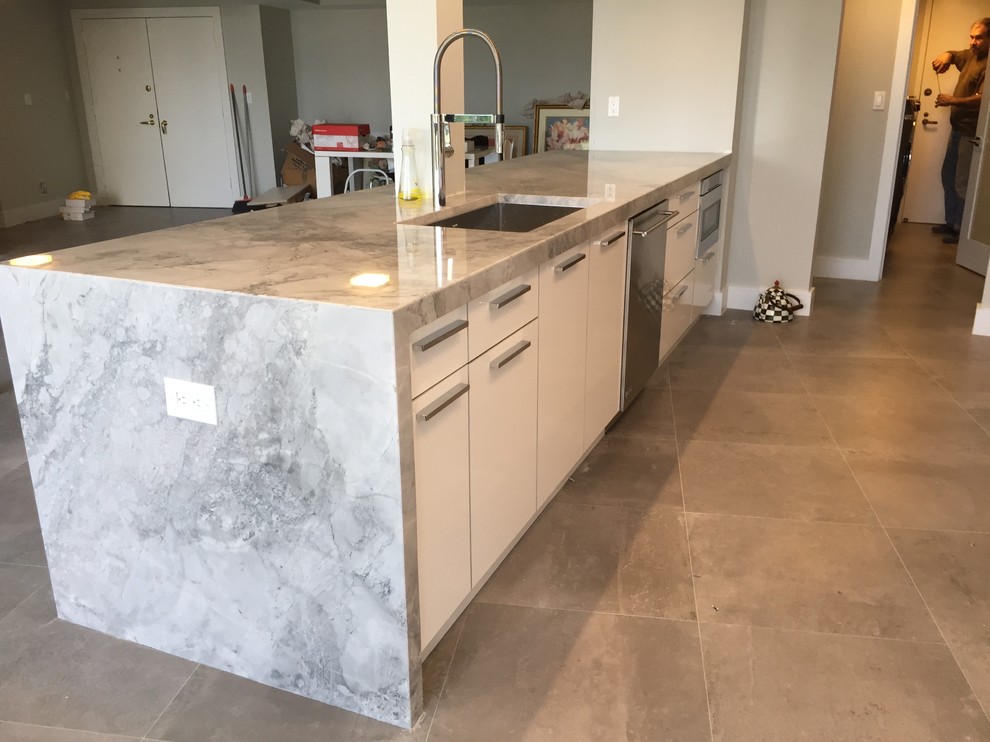 Inspiration for a medium sized contemporary galley open plan kitchen in Miami with a submerged sink, flat-panel cabinets, white cabinets, marble worktops, metallic splashback, porcelain splashback, stainless steel appliances, ceramic flooring, an island and grey floors.