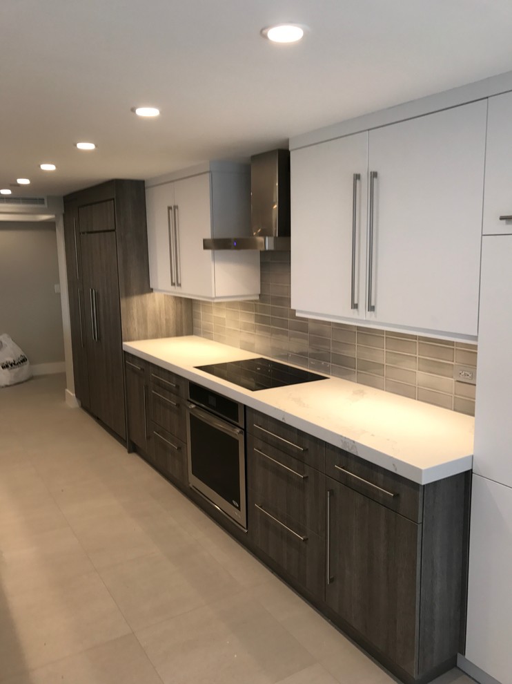 Design ideas for a medium sized contemporary galley enclosed kitchen in Miami with a submerged sink, flat-panel cabinets, white cabinets, composite countertops, grey splashback, porcelain splashback, stainless steel appliances, ceramic flooring, an island and grey floors.