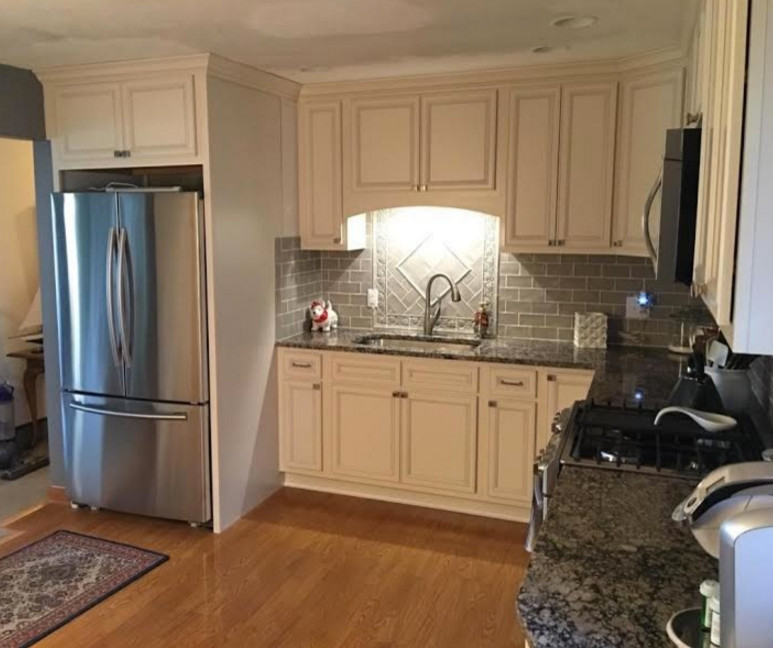 Mid-sized elegant l-shaped light wood floor eat-in kitchen photo in Cleveland with an undermount sink, recessed-panel cabinets, white cabinets, granite countertops, beige backsplash, subway tile backsplash, stainless steel appliances and no island