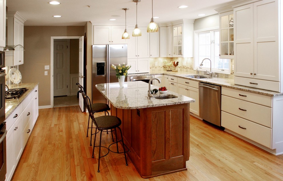 Exempel på ett stort lantligt kök, med en dubbel diskho, skåp i shakerstil, vita skåp, granitbänkskiva, beige stänkskydd, stänkskydd i keramik, rostfria vitvaror, ljust trägolv, en köksö och brunt golv
