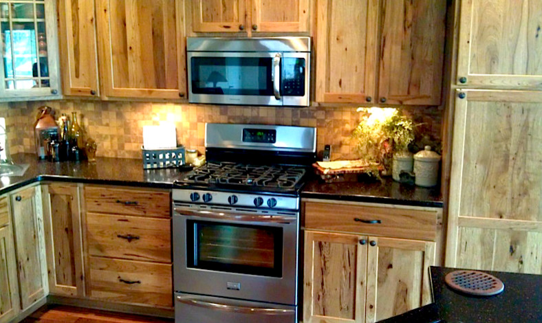 Exemple d'une cuisine nature en bois clair avec un placard à porte shaker, une crédence multicolore, une crédence en carrelage de pierre, un électroménager en acier inoxydable, un sol en bois brun et îlot.