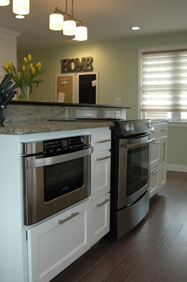 Exempel på ett avskilt, mellanstort klassiskt l-kök, med en undermonterad diskho, luckor med infälld panel, vita skåp, granitbänkskiva, flerfärgad stänkskydd, stänkskydd i glaskakel, rostfria vitvaror, mellanmörkt trägolv, en köksö och brunt golv
