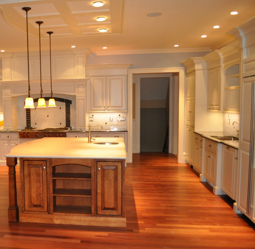 Bild på ett stort funkis kök, med en enkel diskho, luckor med upphöjd panel, vita skåp, granitbänkskiva, vitt stänkskydd, mörkt trägolv och en köksö