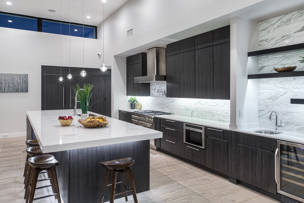 Inspiration for a large contemporary single-wall kitchen/diner in Phoenix with a submerged sink, flat-panel cabinets, black cabinets, composite countertops, light hardwood flooring, an island, grey splashback, stone slab splashback and stainless steel appliances.